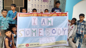 Photo of children working with SARTHI in Patna, India holding a banner with fingerprint artwork for the I Am Somebody campaign.